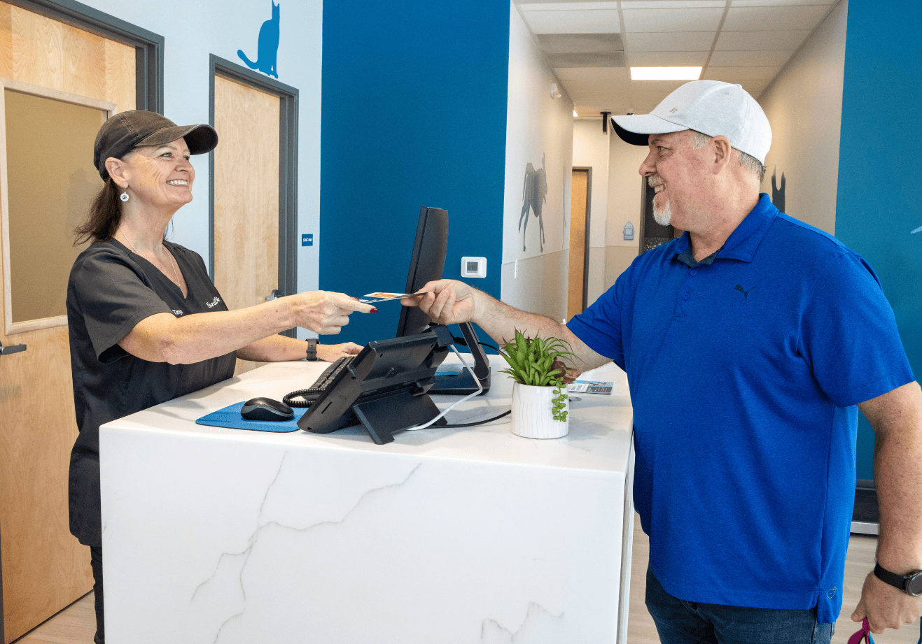 Man wearing baseball cap receiving Livewell pamphlet from receptionist